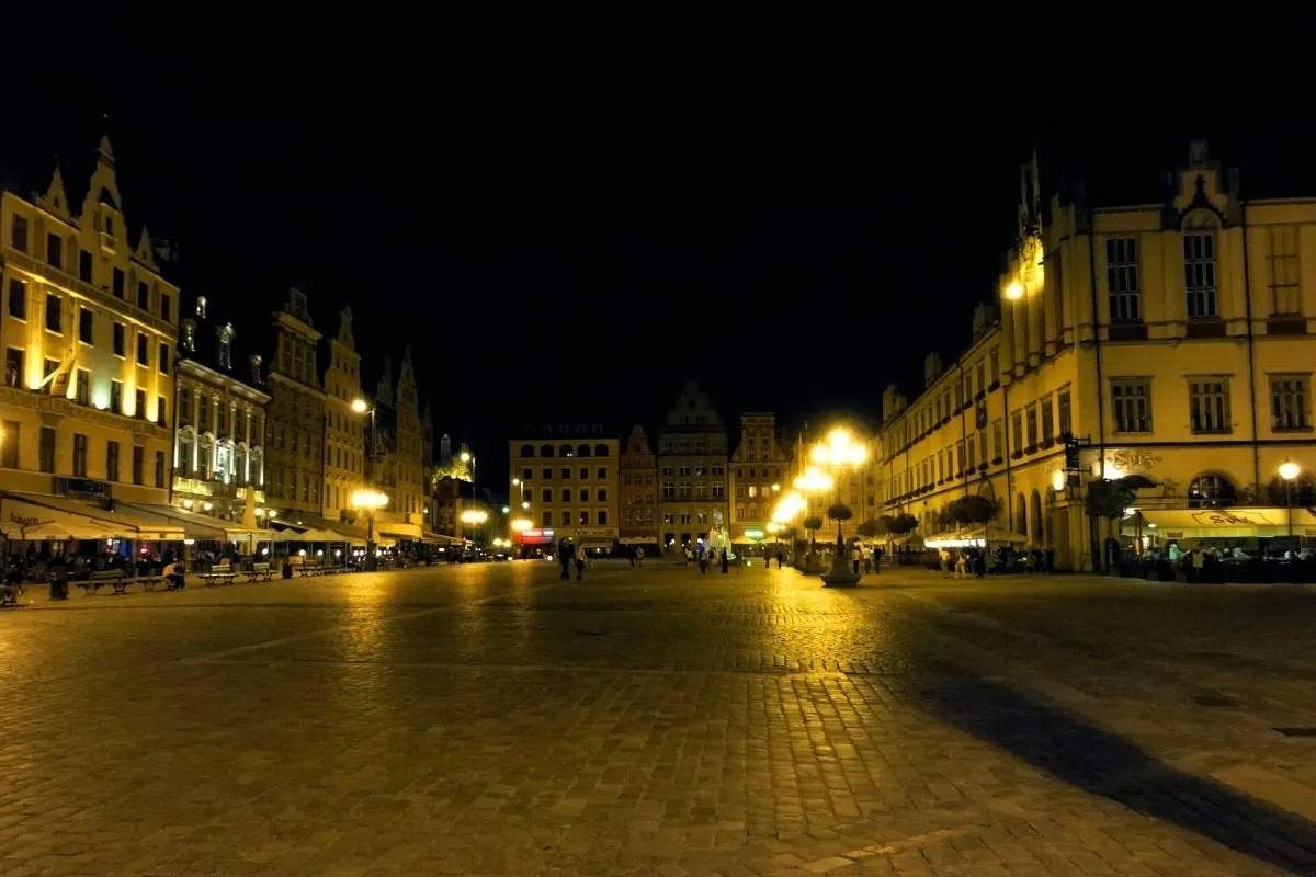 Pusty, oświetlony latarniami Rynek we Wrocławiu nocą, z kamienicami po obu stronach
